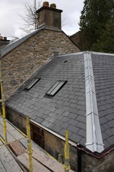 A close up of an attic room with the roof being repaired with new slate tiles
